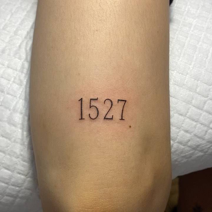 "1527" lettering tattoo on the tricep.