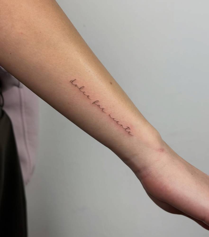 "Dolce far niente" lettering tattoo located on the wrist.