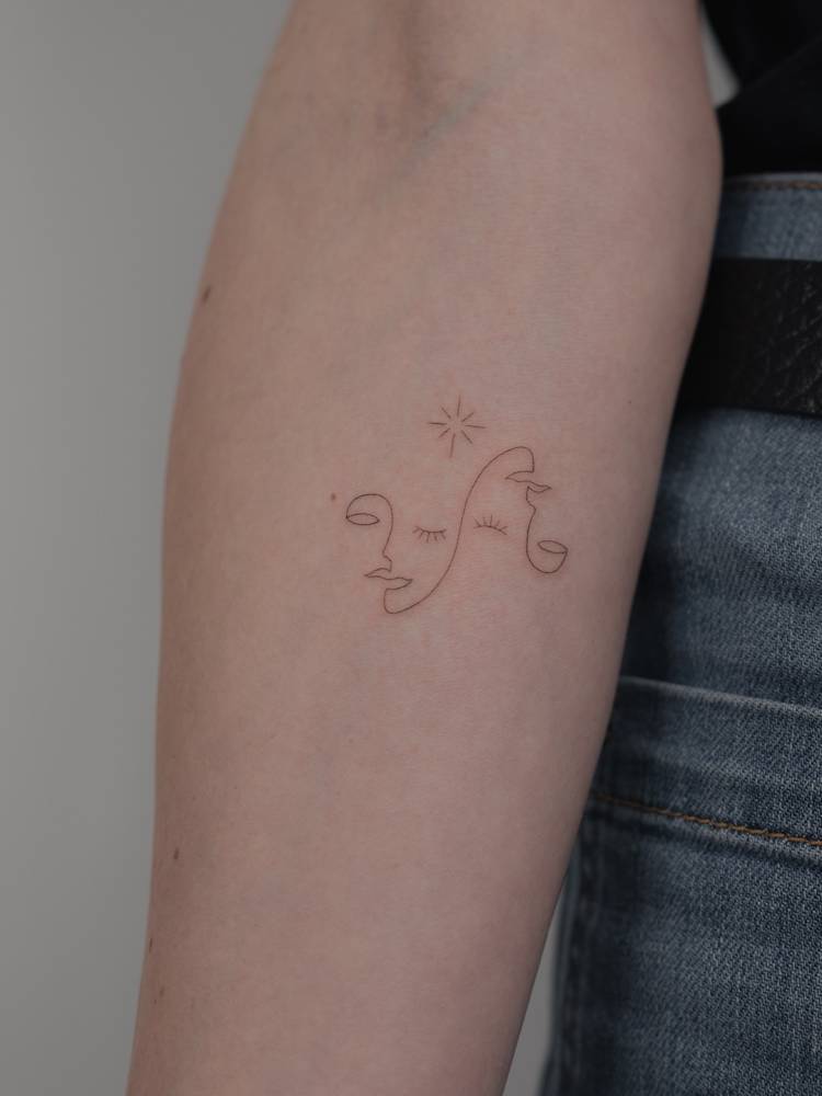 Fine line style abstract faces tattoo located on the inner forearm.