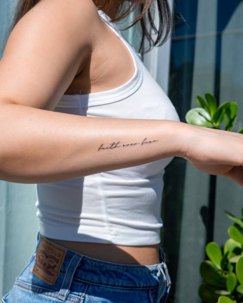 "Faith over fear" lettering tattoo placed on the wrist.