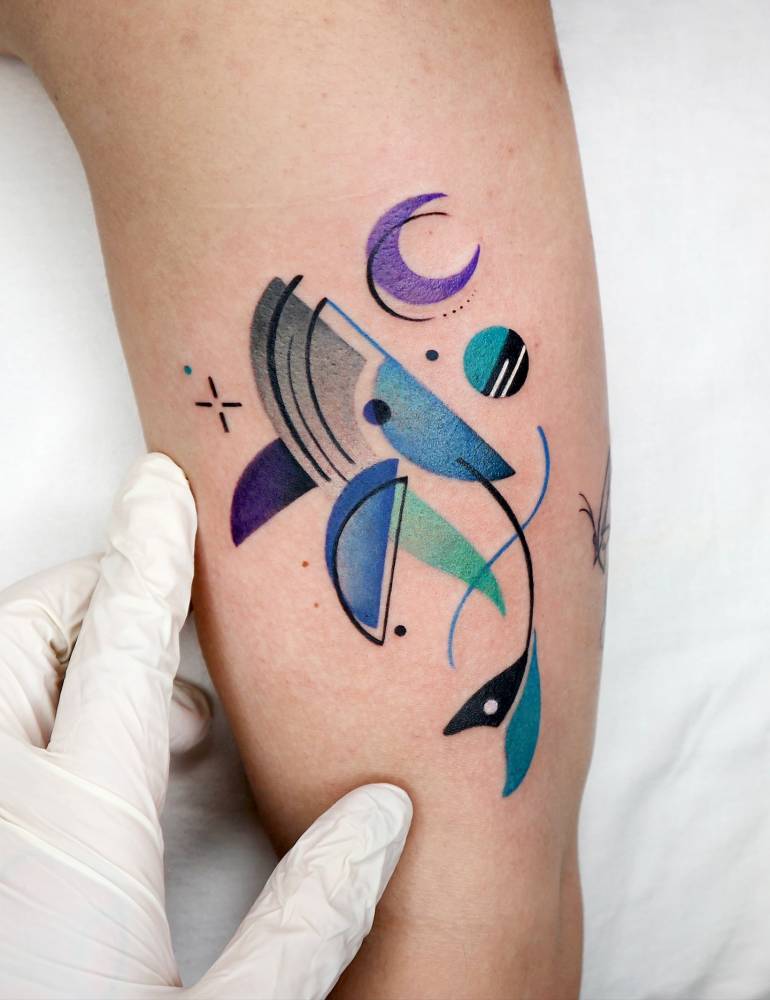 Geometric style whale tattoo located on the upper arm.