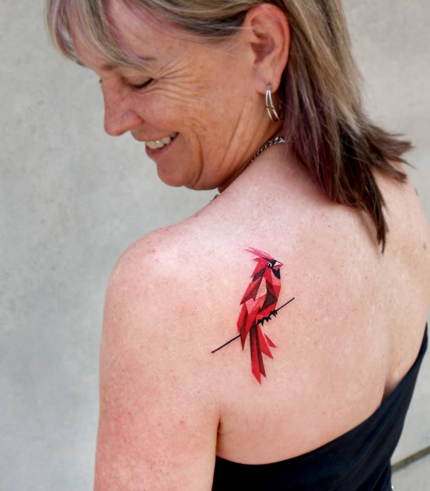 Low poly cardinal tattoo in pop art style located on the shoulder blade.