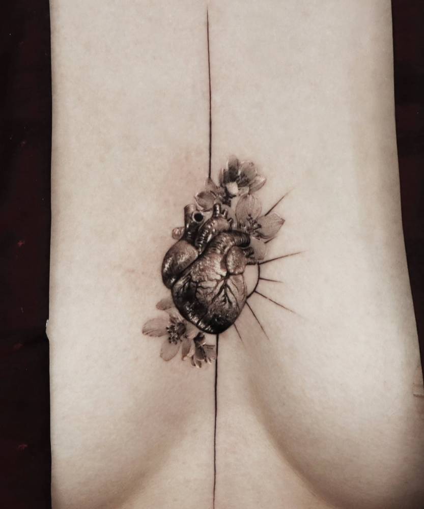 Anatomical heart with flowers tattoo in micro-realistic style located on the sternum.