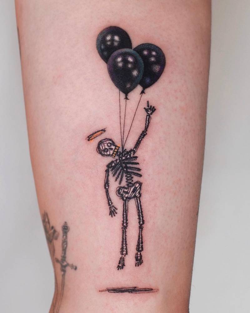 Skeleton and balloons tattoo located on the inner arm.
