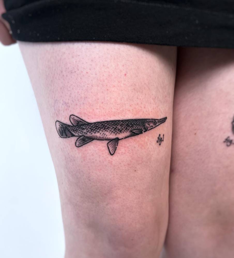 Alligator gar tattoo located on the thigh, engraving style.