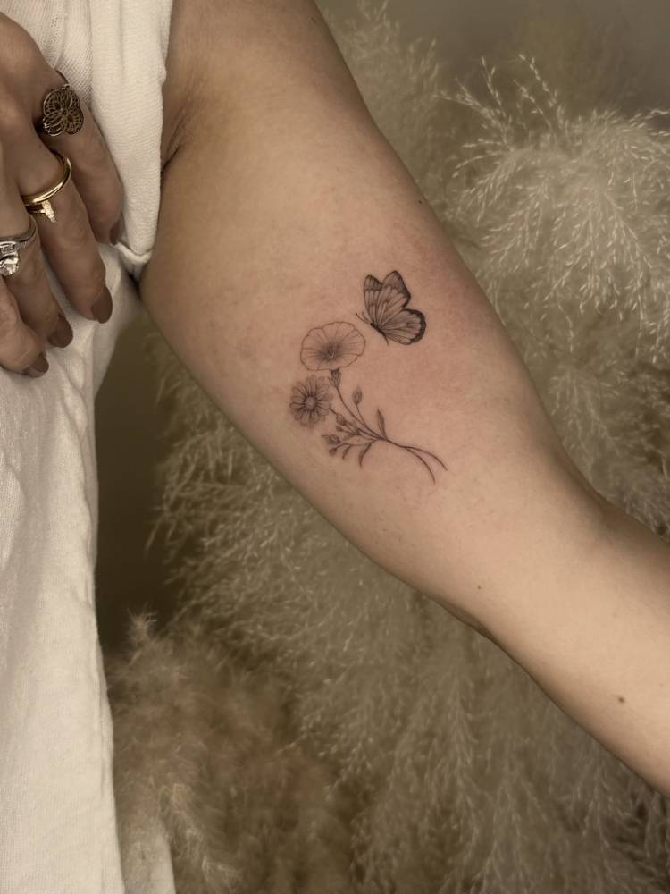 Illustrative style flowers and butterfly tattoo located on the inner arm.