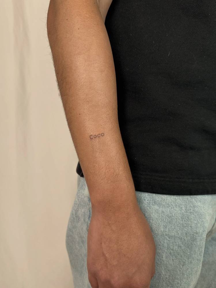 "Coco" lettering tattoo located on the forearm.
