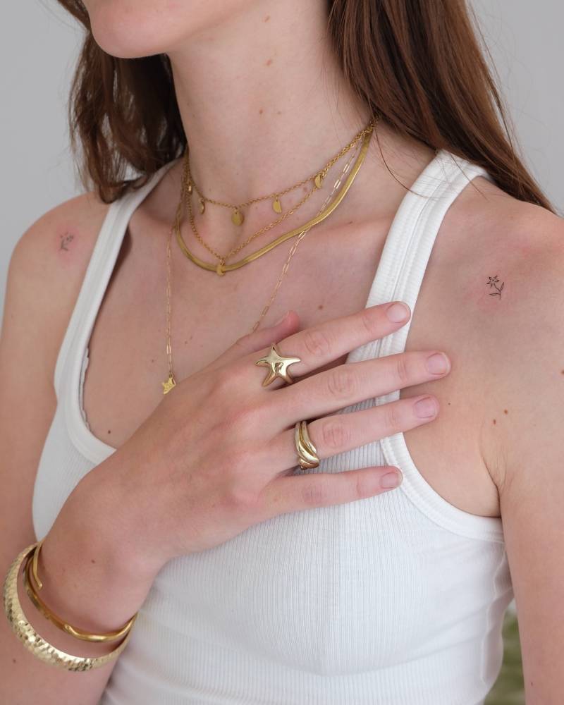 Tiny minimalistic flower tattoo located on the shoulder.