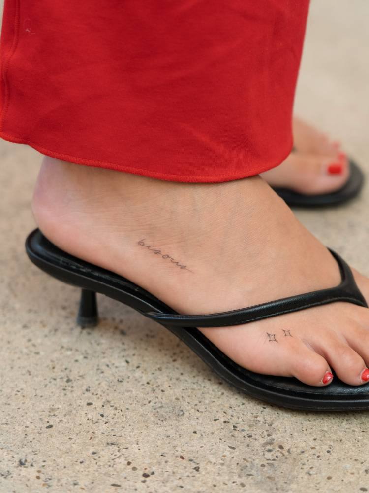 Word "bisous" and minimalistic stars tattooed on the foot.
