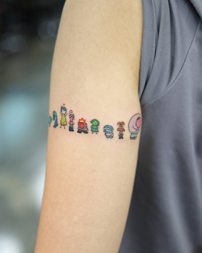 Cartoon style inside out tattoo located on the upper arm.