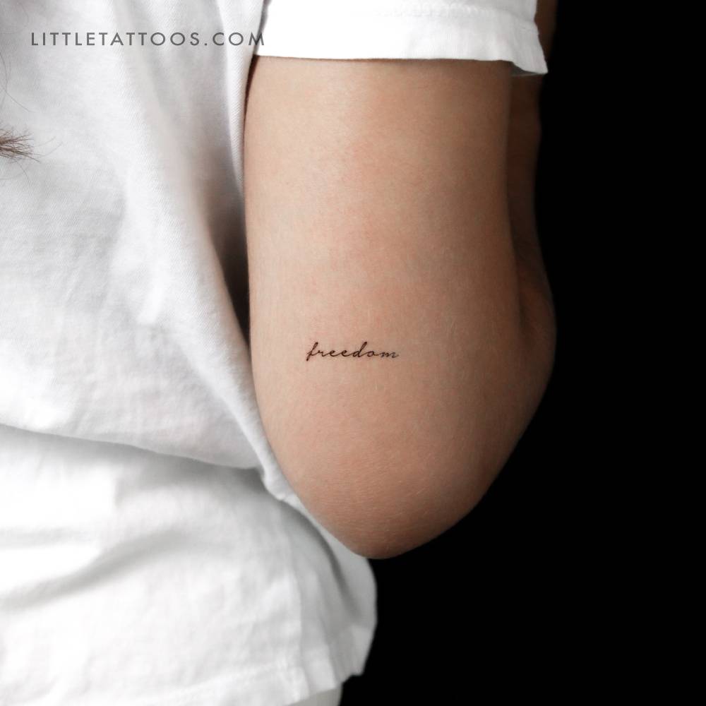 Word "freedom" in handwritten font temporary lettering tattoo.