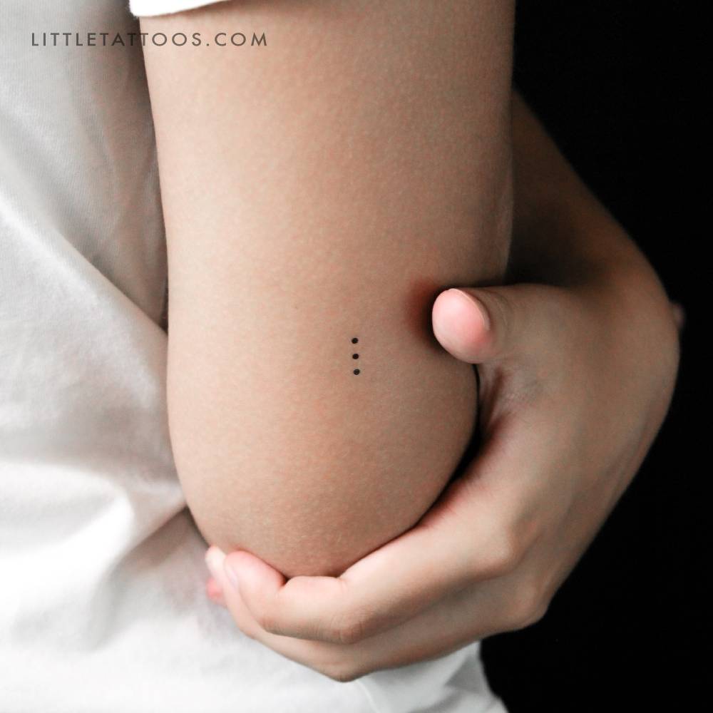 Three tiny dots temporary tattoo located on the tricep.