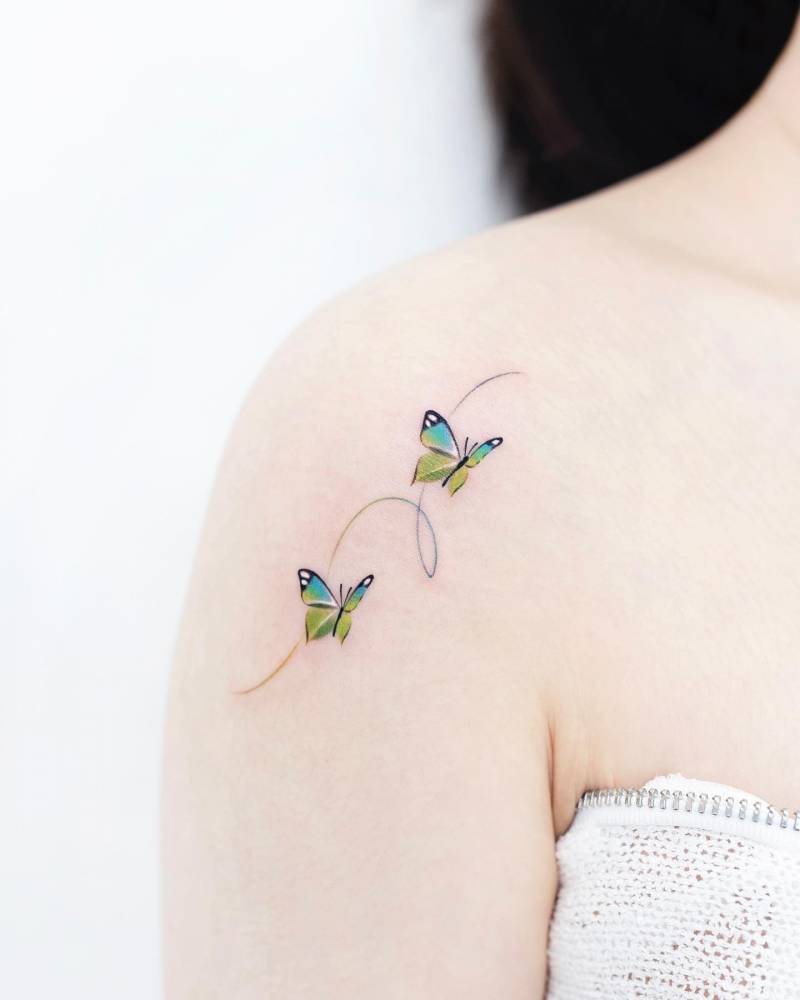 Green butterfly couple tattoo placed on the shoulder.