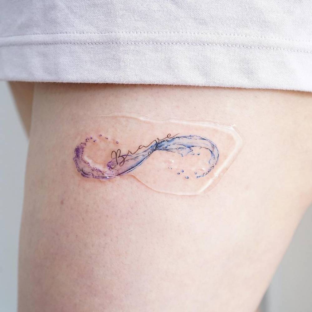 Watercolor infinity wave tattoo on the thigh.