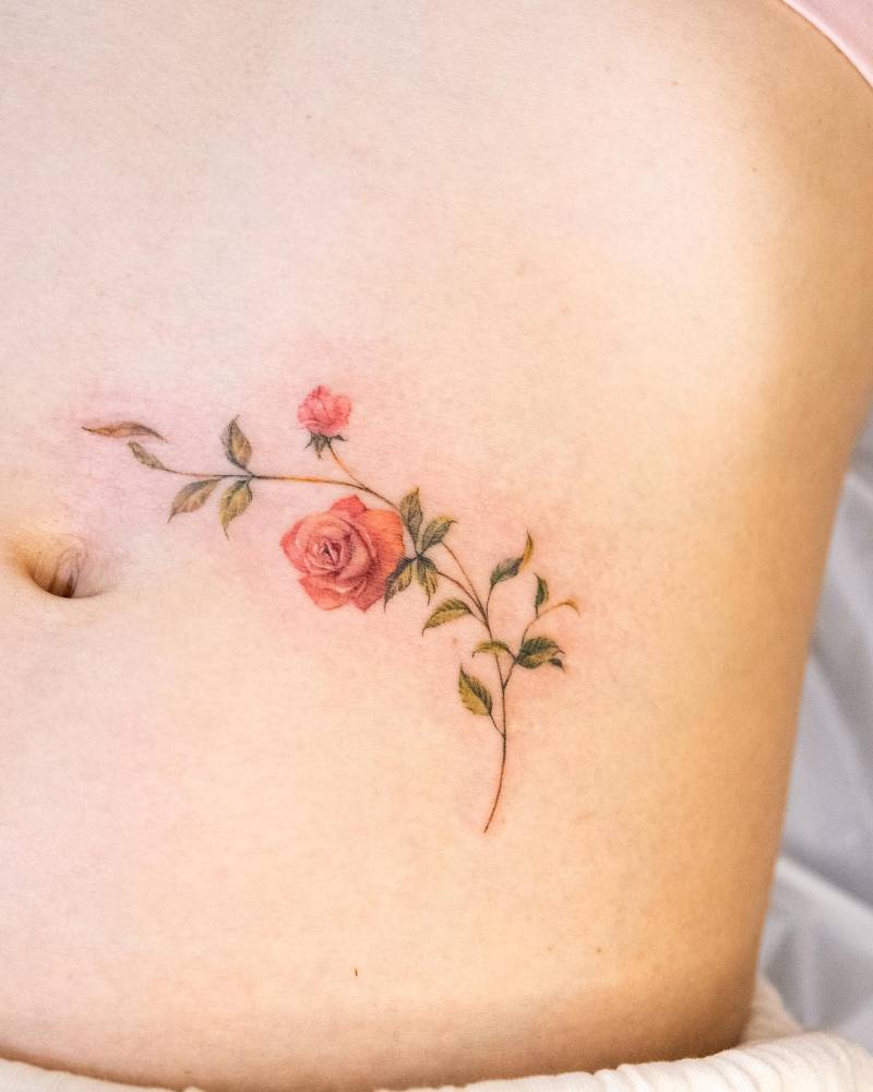 Red roses tattoo located on the waist, done in watercolor style.