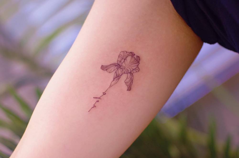 Iris flower and lettering tattoo located on the inner arm.