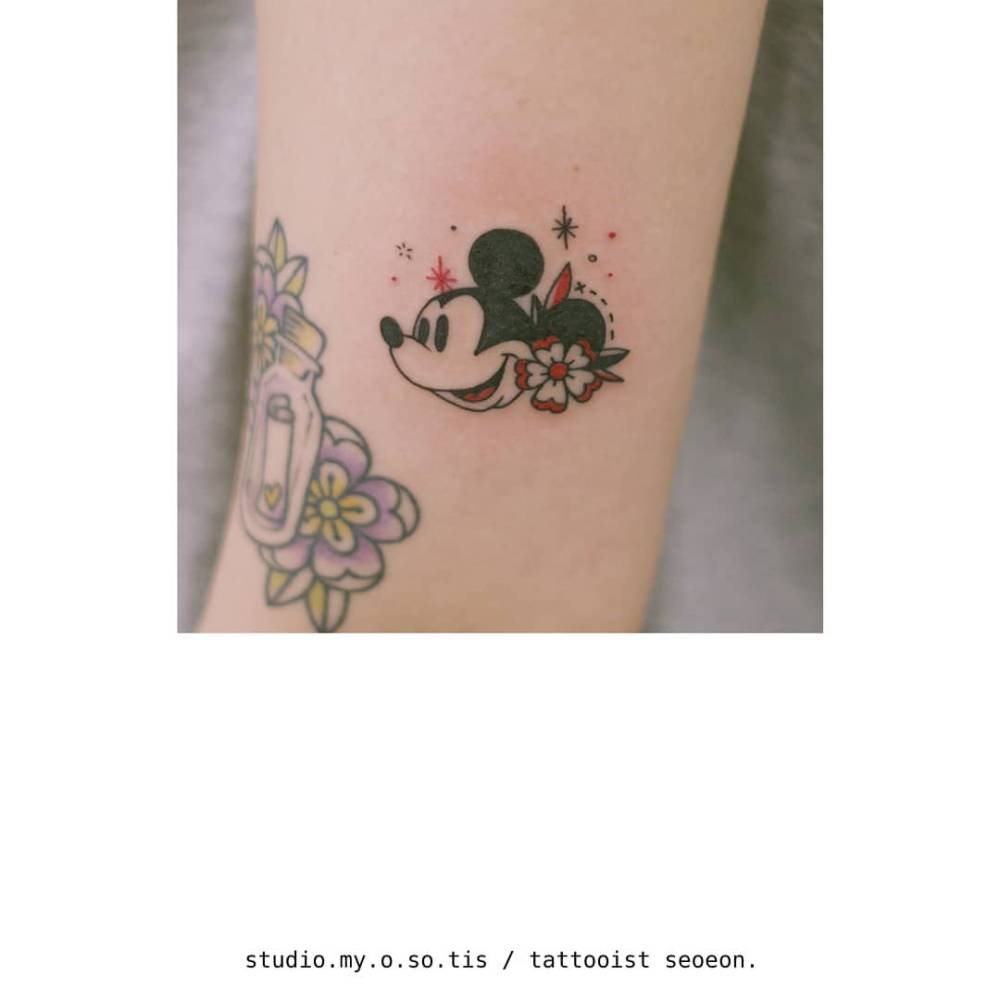 Cartoon style Mickey Mouse portrait tattoo located on the upper arm.