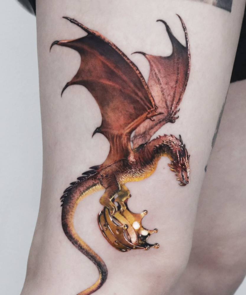 Micro-realistic style dragon and crown tattoo located on the thigh.