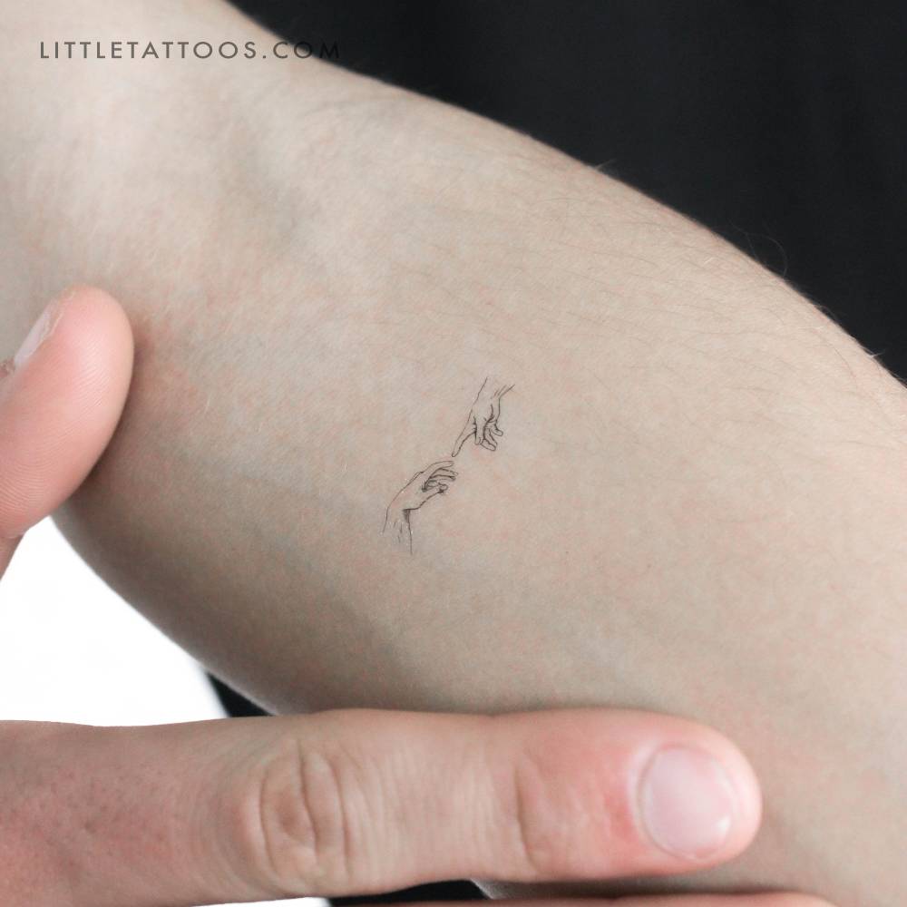Minimalist 'Creation of Adam' hands temporary tattoo located on the inner forearm.