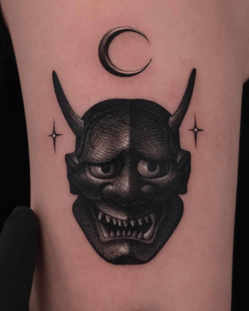 Illustrative style Hannya mask tattoo located on the upper arm.