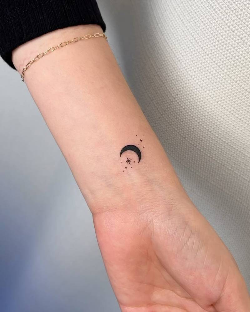 Delicate little crescent moon and stars tattoo located on the wrist.