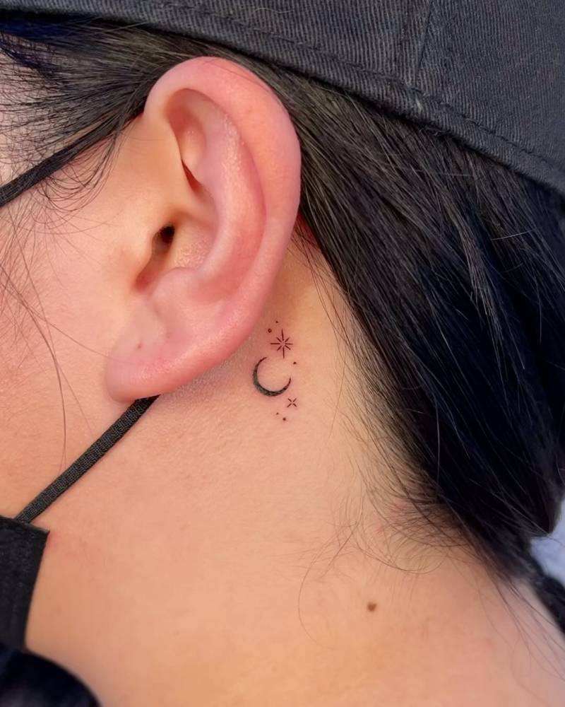 Crescent moon and stars tattoo located behind the ear.