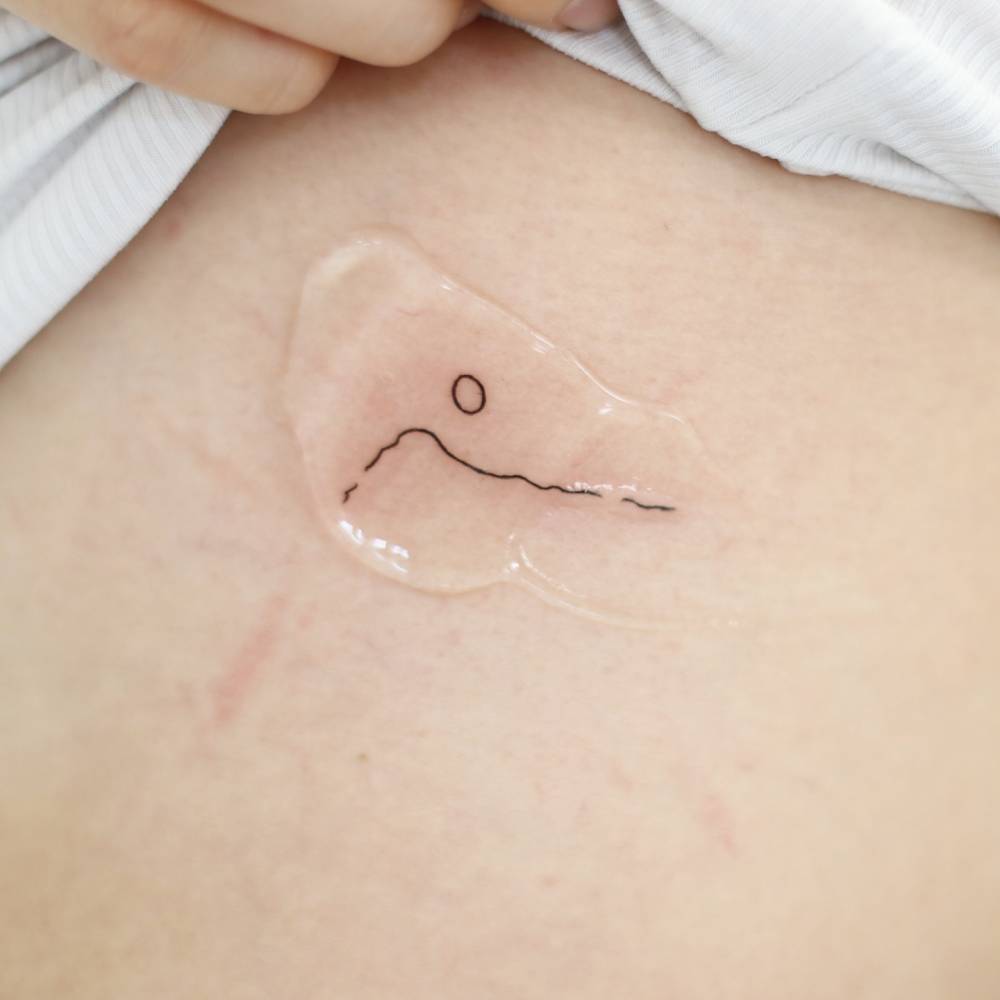 Minimalistic style mountain tattoo placed on the side boob.