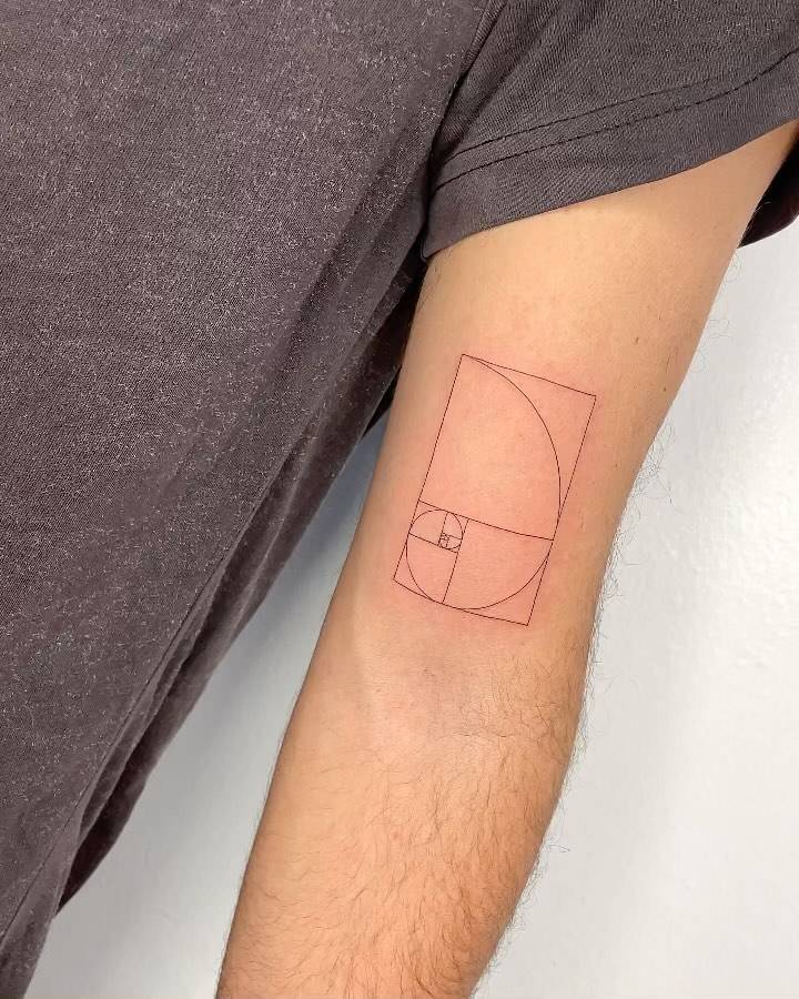 Fine line style golden spiral tattoo placed on the bicep.