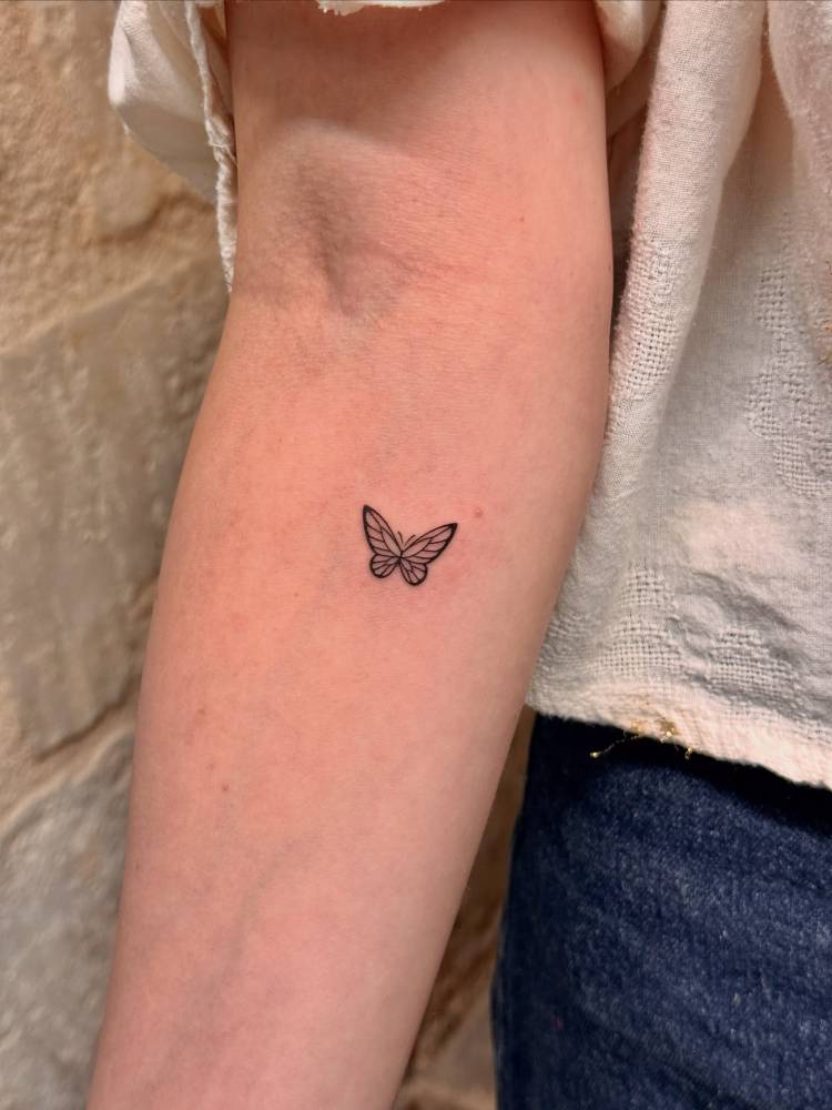 Fine line style butterfly tattoo placed on the inner forearm.