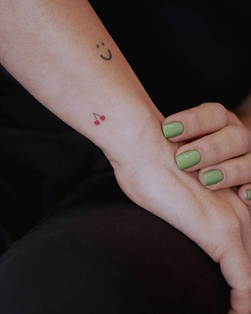 Tiny minimalistic cherries tattooed on the wrist.