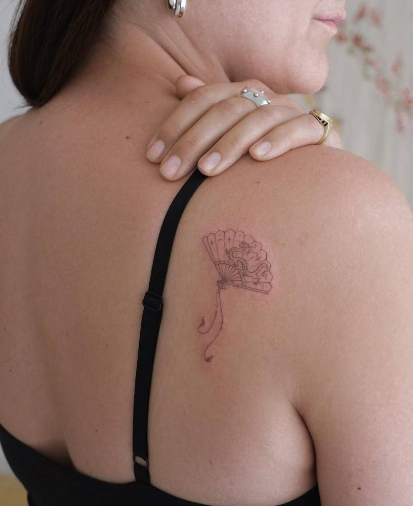Hand fan tattoo located on the shoulder blade, fine line style.