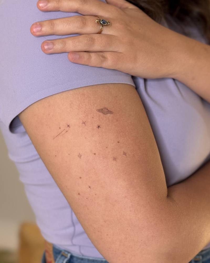 Minimalistic style galaxy tattoo located on the upper arm.