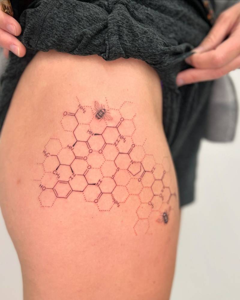 Honeycomb and Oxytocin molecule tattooed on the thigh.