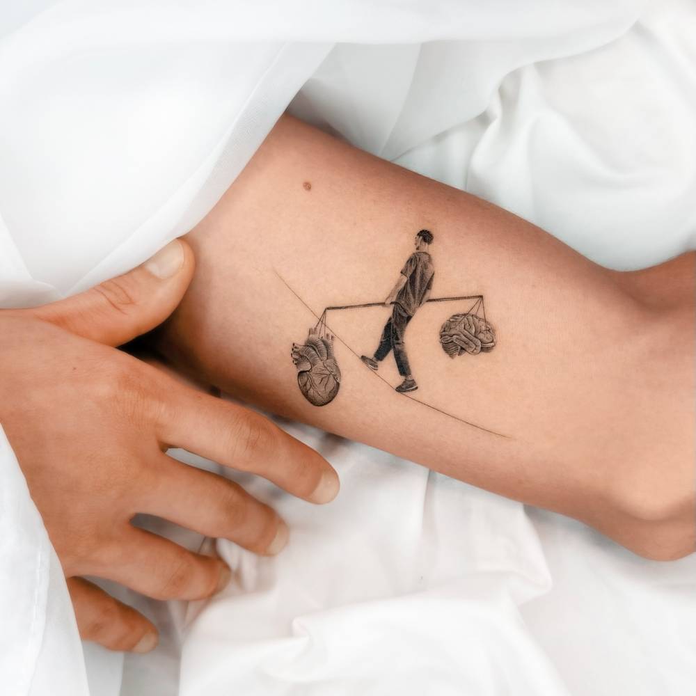 Micro-realistic style brain vs. heart tattoo located on the inner arm.