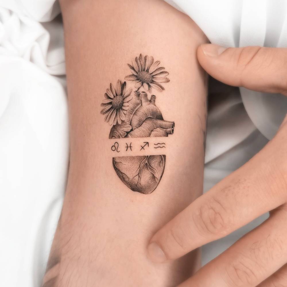Micro-realistic style anatomical heart and flowers tattoo located on the bicep.