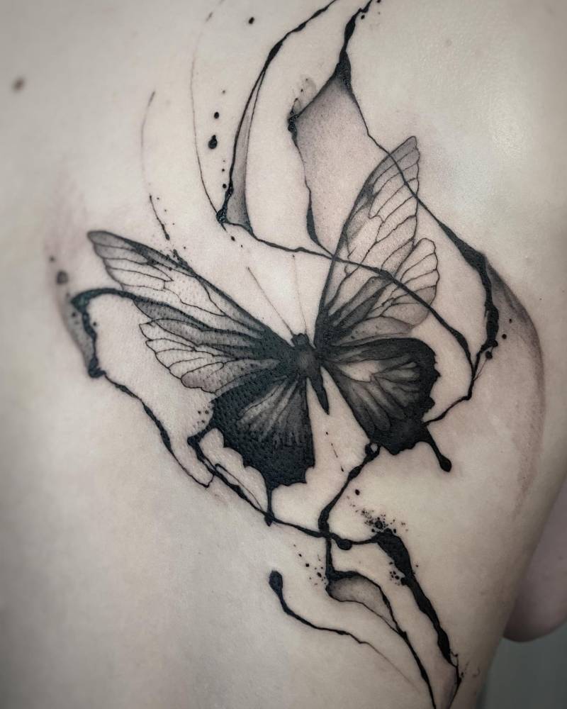 Watercolor style butterfly tattoo located on the shoulder blade.