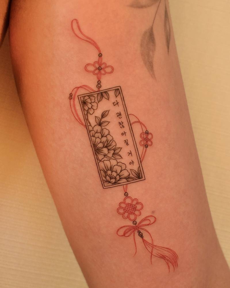 Norigae tattoo located on the inner arm, done in fine line style.