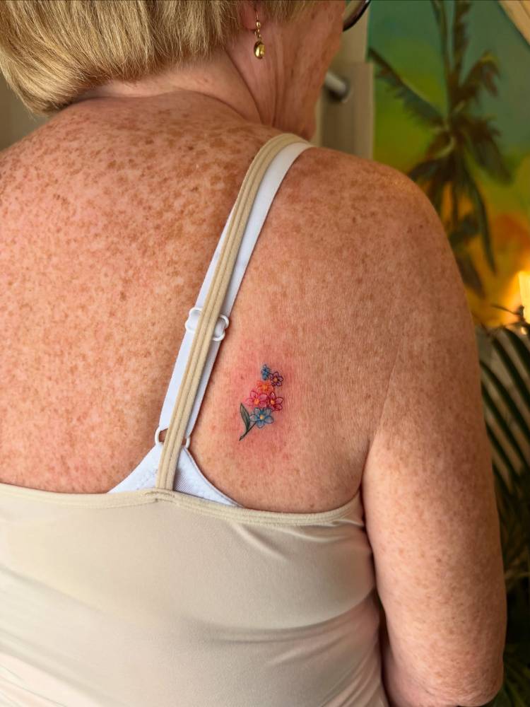 Colorful flower bouquet tattoo located on the shoulder blade.