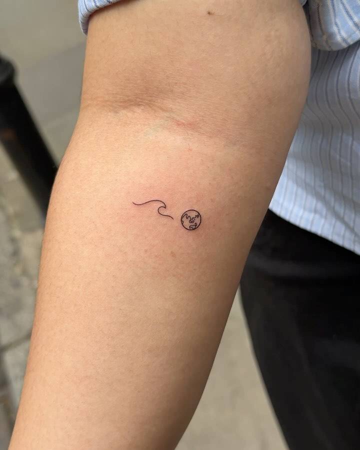 Minimalistic style wave and Earth tattoo located on the inner forearm.