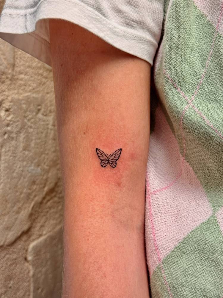 Fine line style butterfly tattoo placed on the bicep.