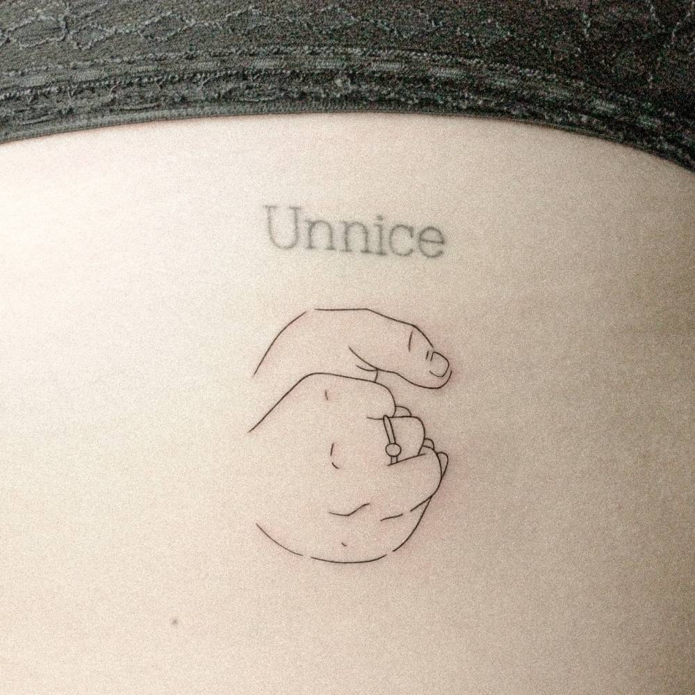 Fine line style holding hands tattoo located on the rib.