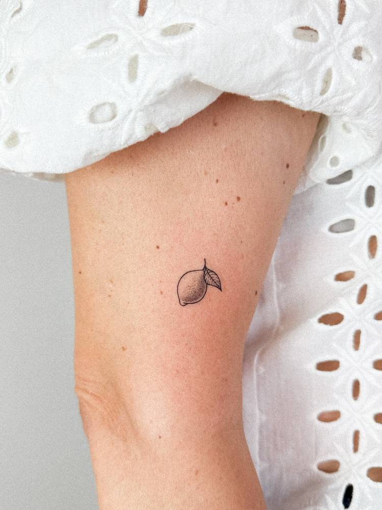 Illustrative style lemon tattoo located on the upper arm.