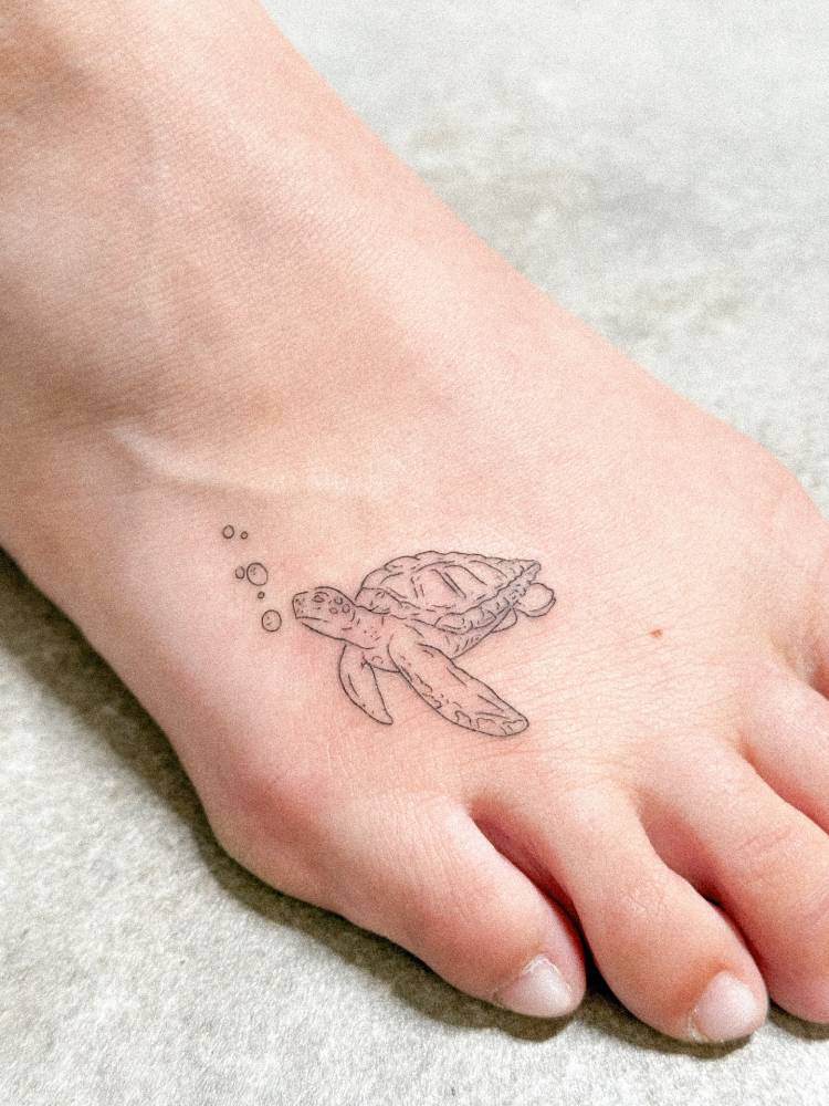 Turtle tattoo located on the foot, done in fine line style.
