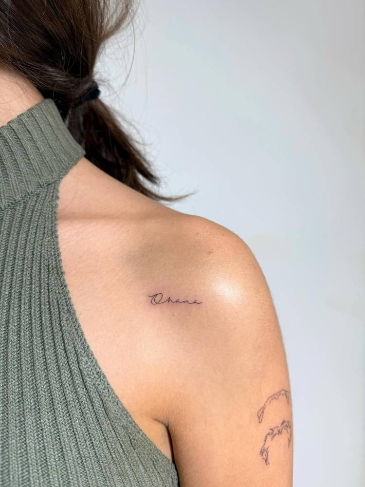 Handwritten font word "ohana" tattooed on the shoulder.