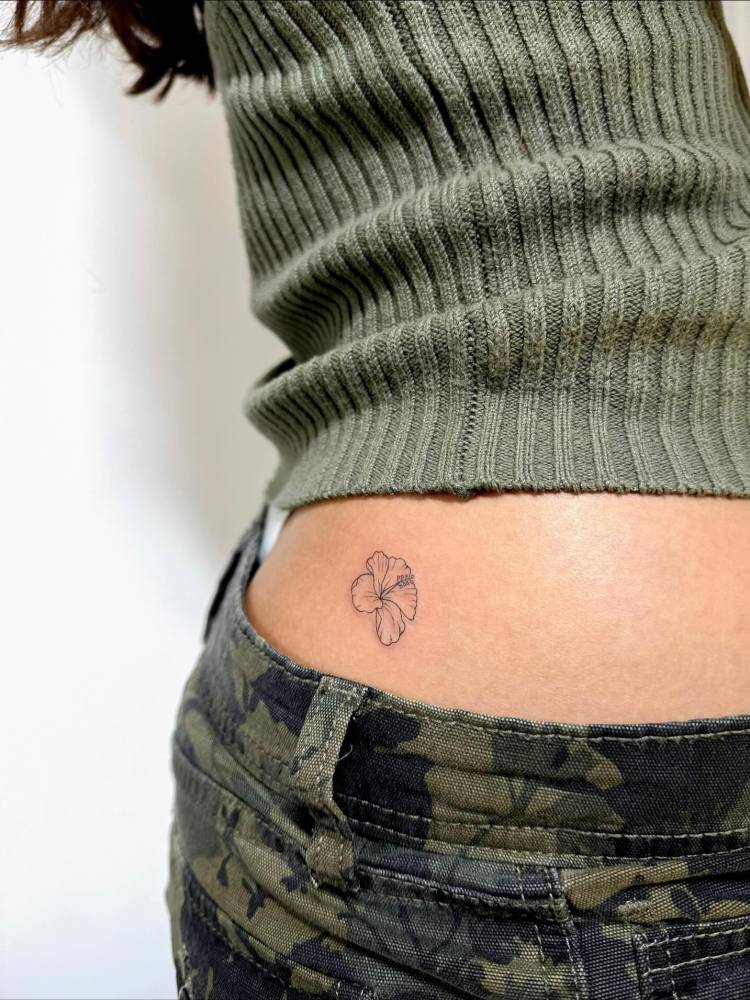 Little hibiscus flower in fine line style tattooed on the hip.