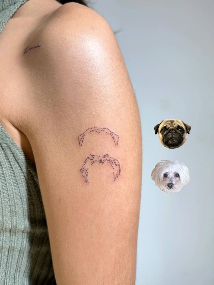 Minimalistic dog ears tattoo located on the upper arm, fine line style.