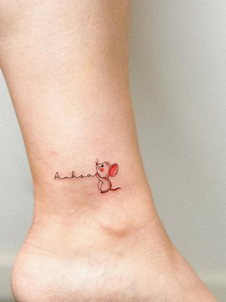 Mouse and name "Ainhoa" tattooed on the ankle.