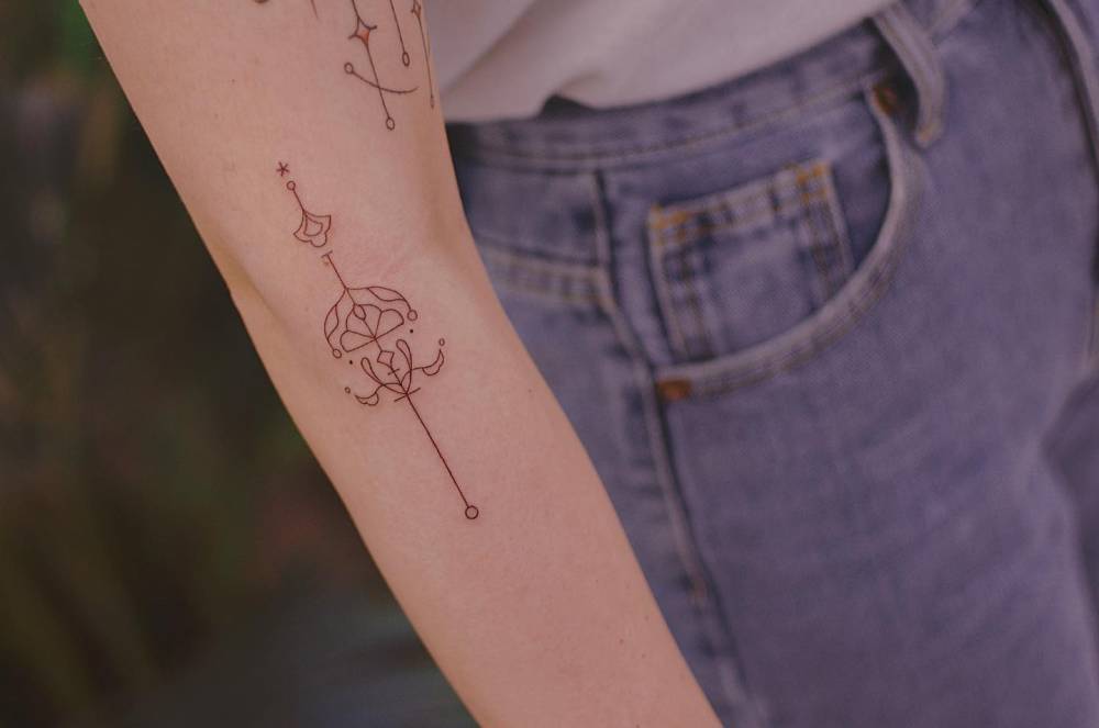 Fine line style ornamental design tattooed on the arm.