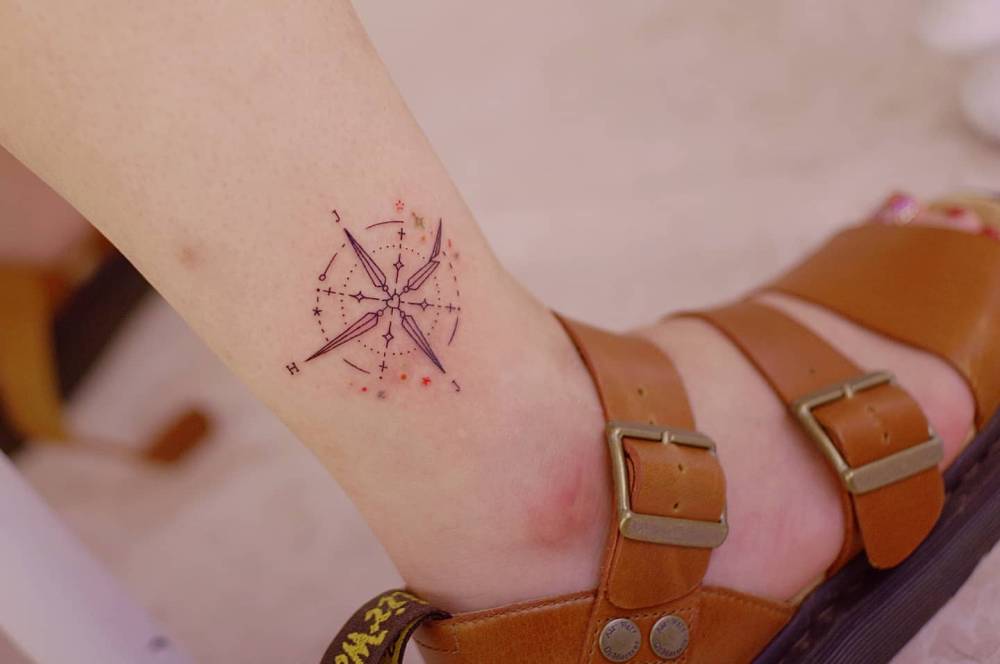 Compass rose tattoo located on the ankle, fine line style.