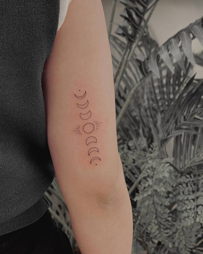 Moon phases tattoo in minimalistic style placed on the tricep.
